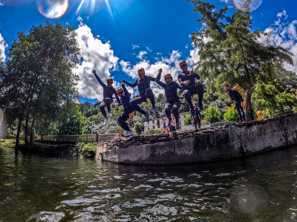 Equipped participants in motion above the water beside the riverbank