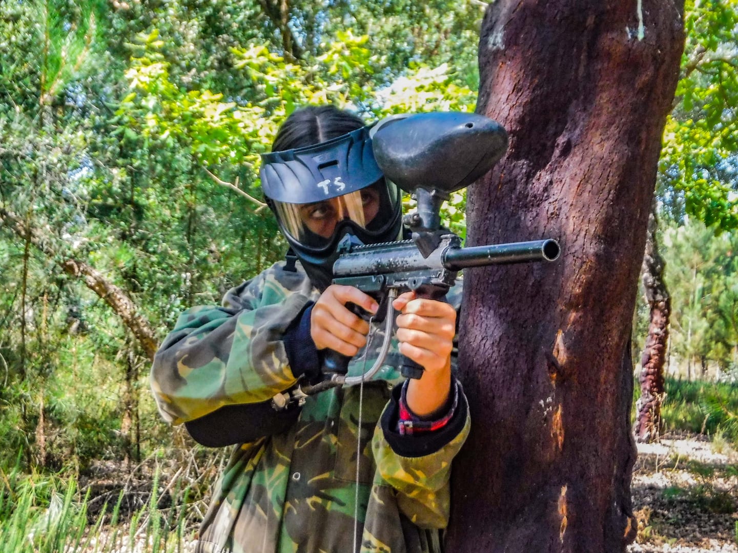 Participante equipado para paintball entre árvores