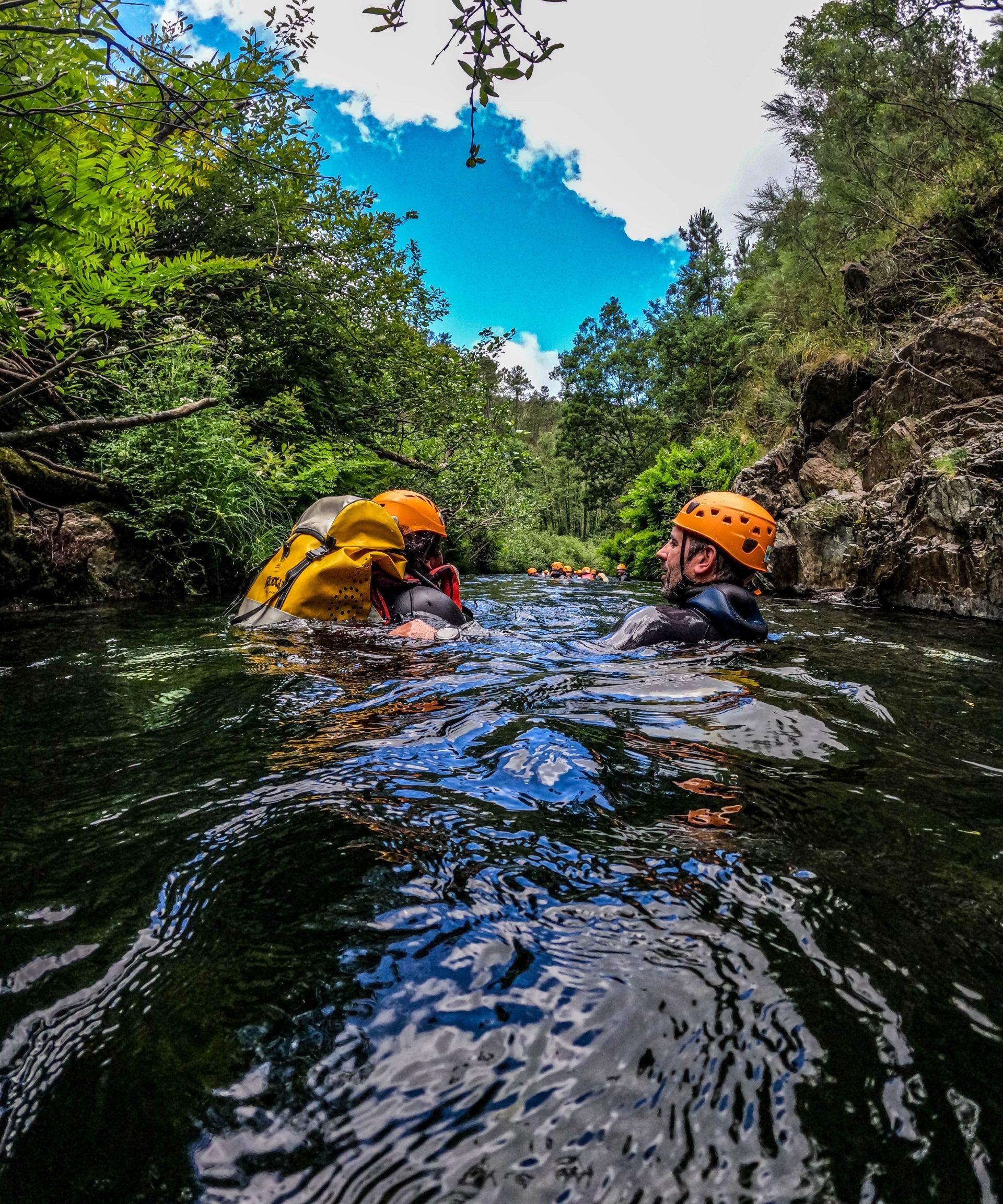 Helmeted participants in the water between the rocky banks of the Water Walking route
