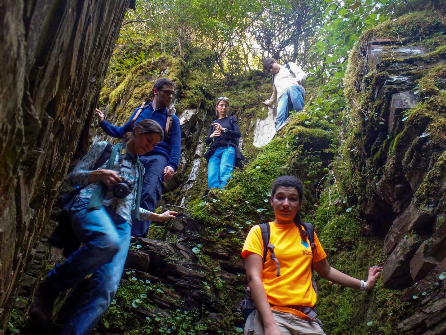 Group making their way through a rocky passage surrounded by vegetation.