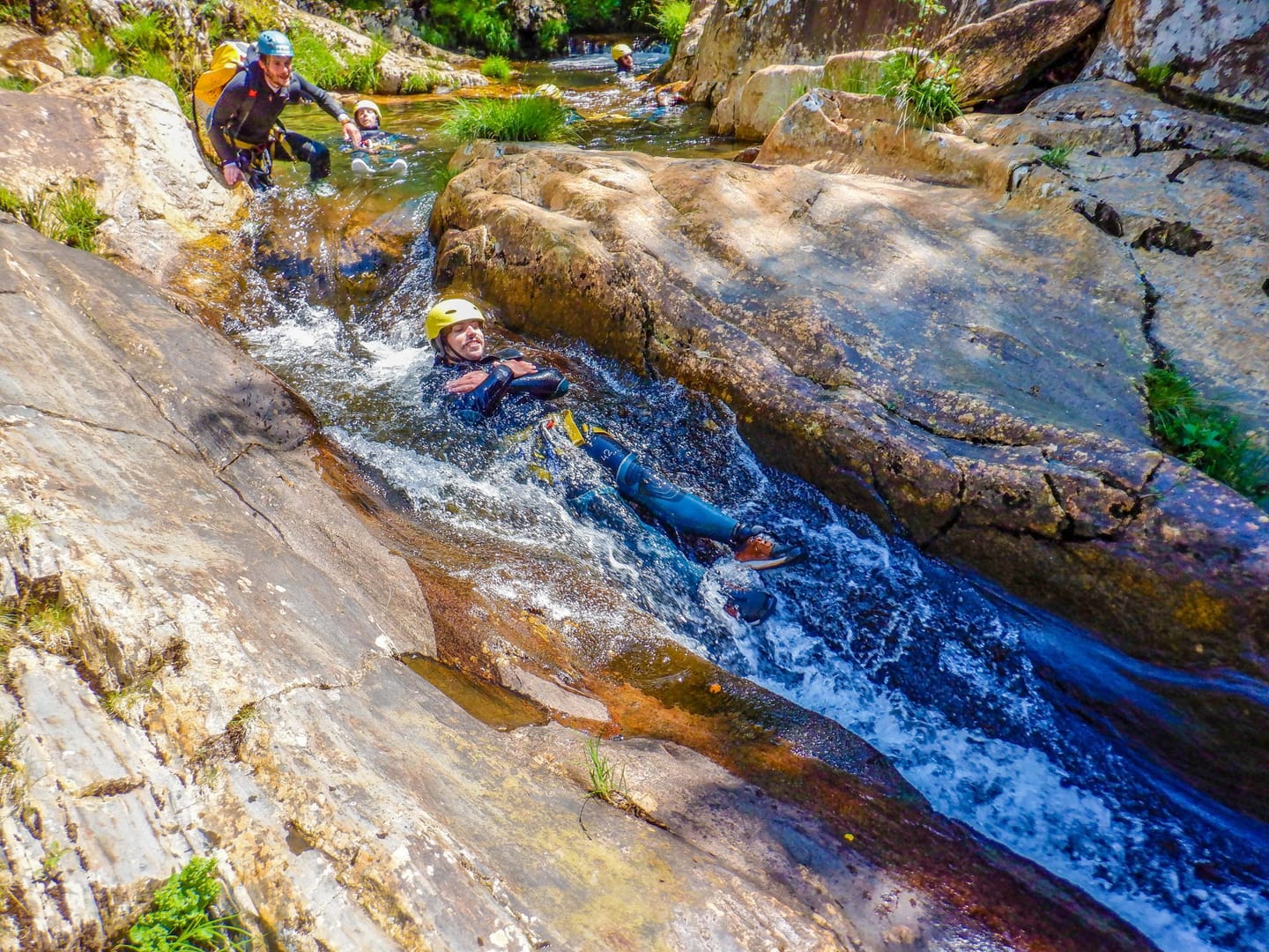 Participant descending a water passage between rocks at Frades